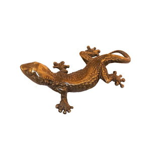 An image of a brass gecko-shaped knob against a neutral background. The knob features detailed design resembling a gecko, adding a touch of whimsy and nature-inspired charm to furniture or drawers.