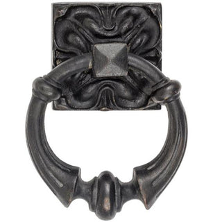 A decorative brass door knocker with intricate, ornate detailing. The design features elegant patterns and textures, giving it a sophisticated and timeless look. The knocker has a smooth, polished surface with a warm golden tone. A sturdy, rounded ring hangs from the center, easy to grasp and use. This piece combines beauty and functionality, adding a refined touch to any front door