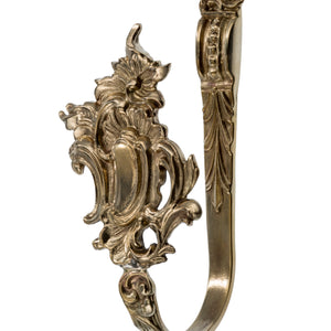 This curtain tieback is made from solid brass with a smooth, polished finish. It has a decorative design that feels both elegant and substantial in the hand, providing a secure way to hold back curtains. The brass material offers a warm, timeless touch, making this tieback both functional and a stylish accent for any room.