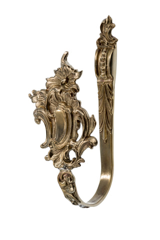 This curtain tieback is made from solid brass with a smooth, polished finish. It has a decorative design that feels both elegant and substantial in the hand, providing a secure way to hold back curtains. The brass material offers a warm, timeless touch, making this tieback both functional and a stylish accent for any room.