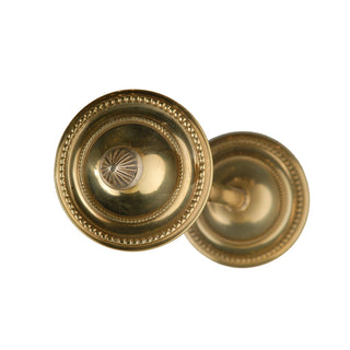 A circular brass tieback with a smooth, polished surface and minimalist design. The tieback has a clean, round shape that feels sturdy yet elegant to the touch, providing a refined accent to hold curtains in place with subtle sophistication.