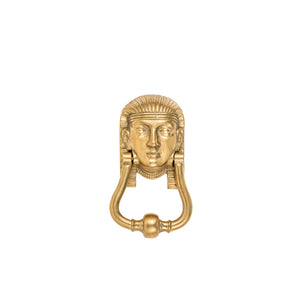 A solid brass door knocker featuring a detailed Sphinx design. The Sphinx has a regal, majestic appearance with a serene face, intricate hair, and a smooth, polished surface. Below the figure, the knocker ring hangs, sturdy and easy to grasp. The brass material gives it a warm, golden tone, adding a touch of elegance and classical charm to any front door.