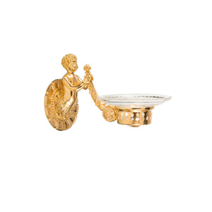 This soap holder features a delicately crafted cut crystal dish, with a smooth surface and faceted edges that create a tactile and elegant feel. The base is made of polished brass, providing a sturdy foundation that is cool and smooth to the touch. An intricately detailed cherub motif adorns the brass base, offering a raised, textured design that adds a decorative and classical element.