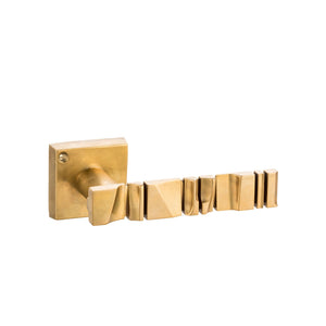 This brass door handle has a smooth, curved surface with an intricate abstract design that you can feel along its length. The brass material is solid and cool to the touch, with a slightly polished finish. The abstract design adds texture and depth, creating a unique tactile experience. The handle is sturdy and comfortable to grip, making it practical for everyday use while adding a touch of artistic elegance to any door.