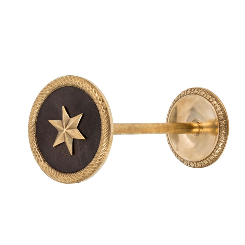 An elegant brass curtain tieback featuring a finely detailed star design. The tieback has a smooth, polished surface, with the star motif delicately raised to add texture. Its classic brass finish reflects a warm glow, perfect for enhancing the beauty and sophistication of any room.
