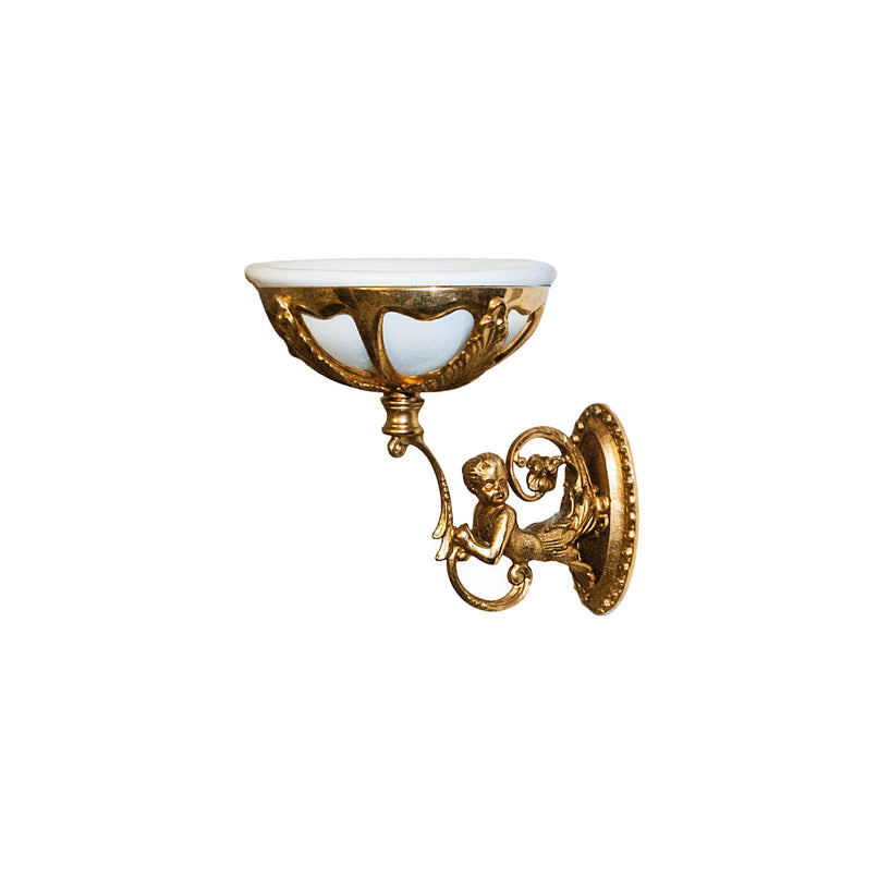 This soap holder combines smooth ceramic and solid brass, featuring a sculpted faun motif for an artistic touch. The ceramic dish is sleek and slightly curved, with raised edges to hold soap securely. The faun detail, located on the brass base, has a textured, raised design that adds a tactile element and classical charm. The brass is polished and cool to the touch, complementing the smooth surface of the ceramic.